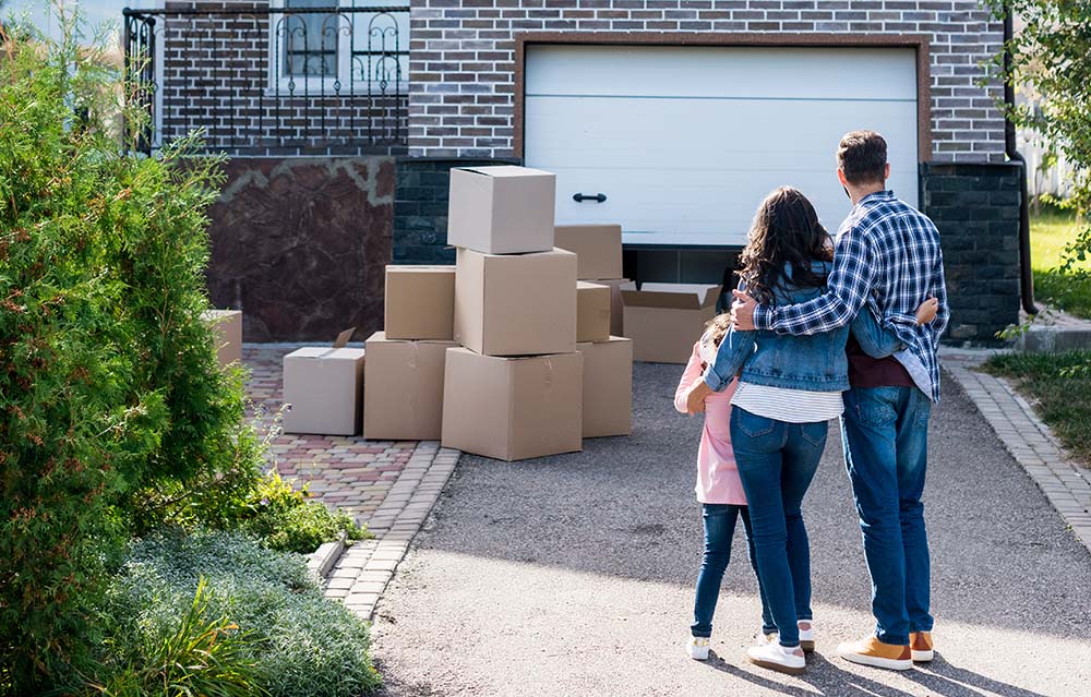 Family with moving boxes in front of their new house after a home inspection